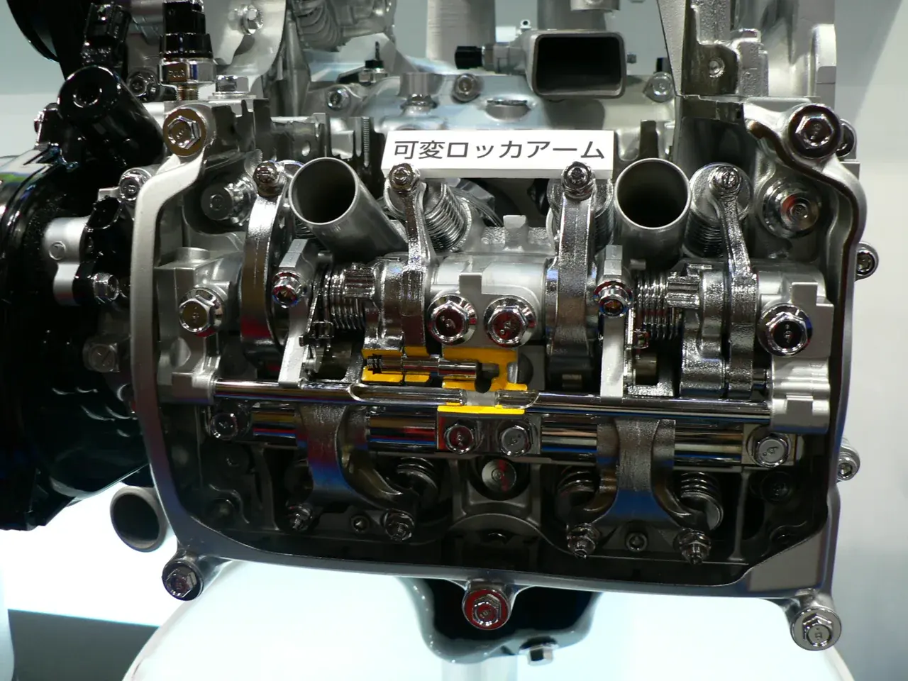 SUBARU EJ25 SOHCのi-AVLS動弁機構の展示。ロッカーアームなどを使ってバルブのリフトを変えます。写真はヘッド側のカムシャフトやロッカーアームを見せた接写です。